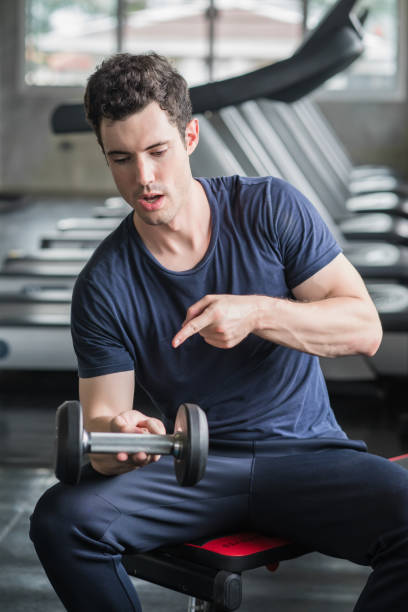 istock man having fun Lifting dumbbell in gym exercise with work out program for healthy 1408560238