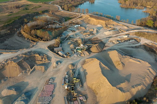 Aerial view of open pit mining site of limestone materials for construction industry with excavators and dump trucks.