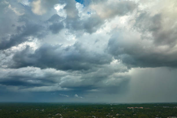 Dark stormy clouds forming on gloomy sky before heavy rainfall over suburban town area.