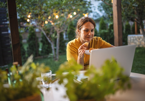 Photo of woman working on laptop from her backyard