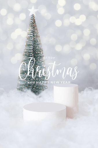 PMerry Christmas greetings and podium or pedestal in the snow with a christmas tree on a bokeh background vertical format
