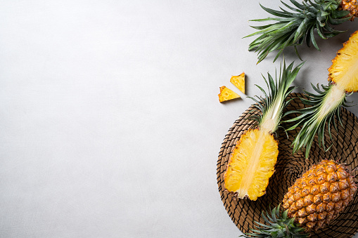 Top view of fresh cut pineapple with tropical leaves on dark blue background.