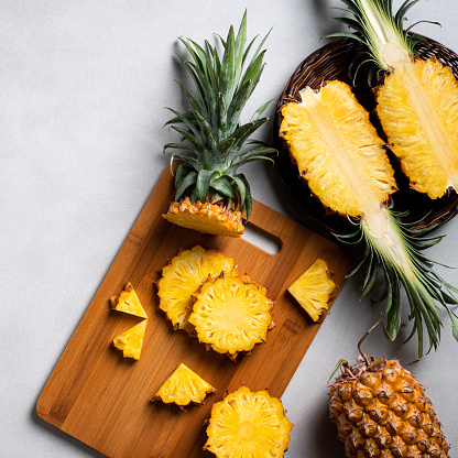 Top view of fresh cut pineapple with tropical leaves on dark blue background.