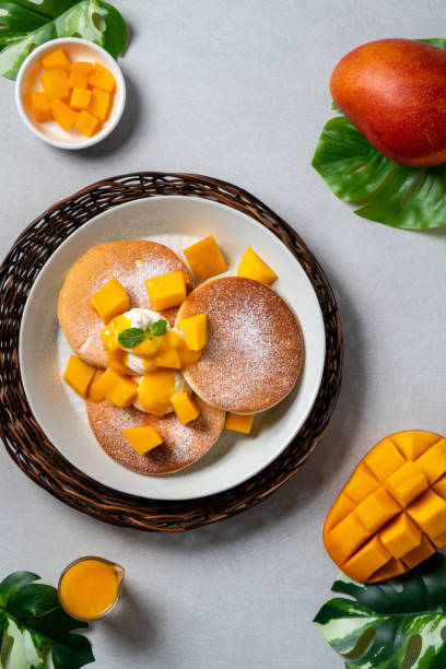 Delicious Japanese souffle pancake with dice mango and jam on white table background.