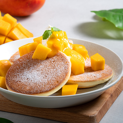 Delicious Japanese souffle pancake with dice mango fruit pulps and jam on white table background.