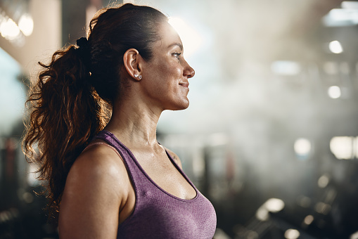 Smiling athletic woman having a sports training in a gym and looking away.