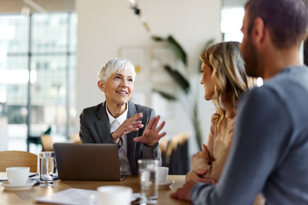 happy female insurance agent talking to a couple on a meeting in the office. - finance senior adult financial advisor meeting imagens e fotografias de stock