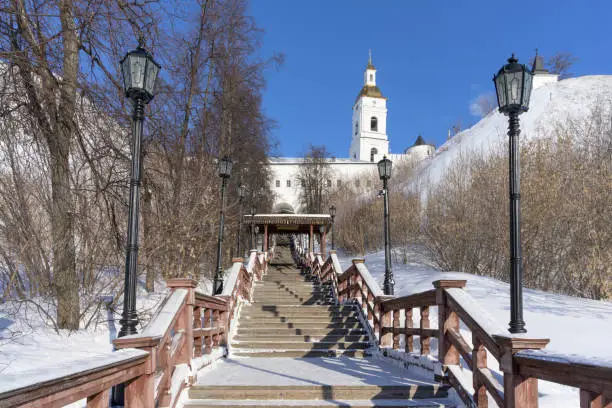 The entrance to the upland part of the city is through a high wooden staircase with carved decorations and lanterns. The ancient city of Tobolsk (Siberia, Russia) in a winter day. Blue sky, bright sun