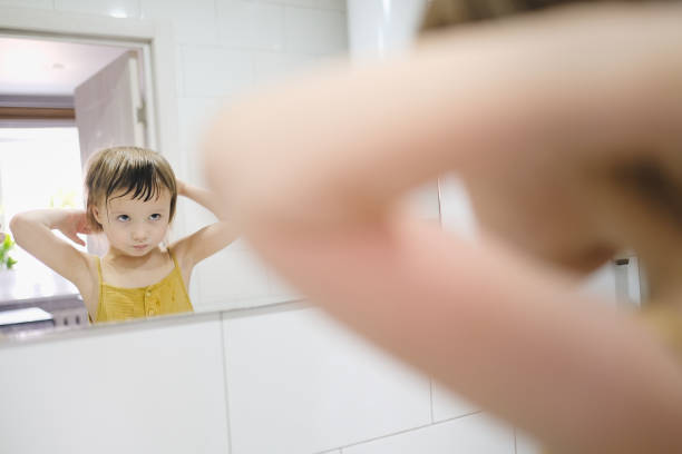 istock Cute toddler baby combs in front of bathroom mirror 1408586593