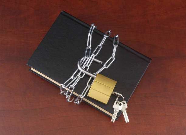 istock Book with chain and padlock on wooden table. 1408588016