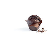 Chocolate muffin in brown paper with chocolate pieces on a white background, copy space