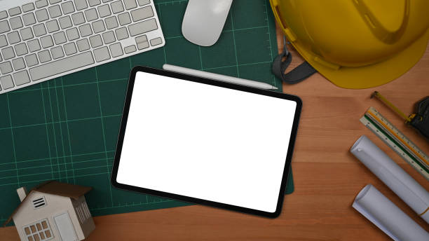 istock Digital tablet, protective helmet and blueprints on a wooden table. Engineer, Architect office desk. 1408588587