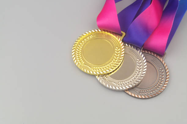 Three medals - gold, silver and bronze with ribbons on gray background, copy space for text.
