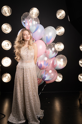 Refined white woman with balloons posing on black background. Studio portrait of attractive curly girl waiting for birthday party.
