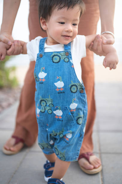 istock Baby boy learning how to walk outdoors making his first steps while mother holds his hands 1408589502
