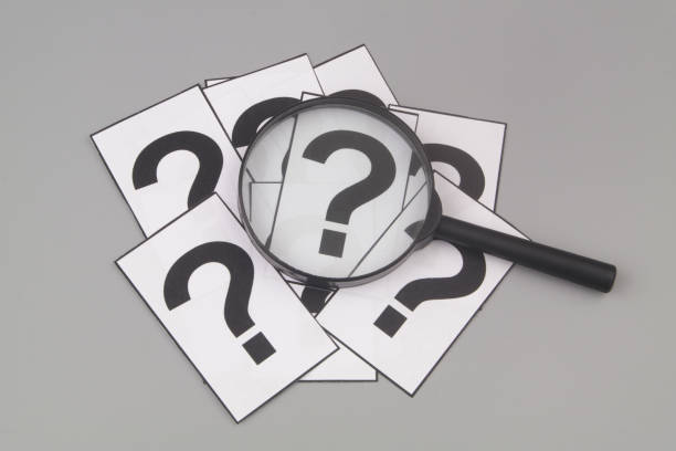 istock Magnifying glass on many question marks on gray background. 1408590042