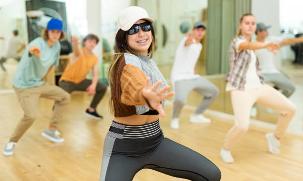 Group of teens rehearsing hip-hop dance in studio Teens training hip-hop dance moves during group rehearsal in studio. dance troupe stock pictures, royalty-free photos & images