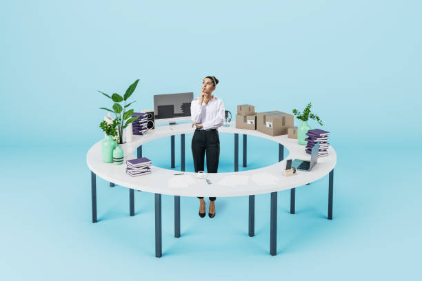 istock Attractive thoughtful young businesswoman standing inside round table with many items on blue wall background. Hobby and occupation choice concept. 1408596242