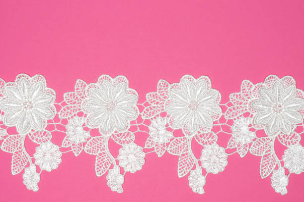 istock White laces with flowers and leaves on pink background isolated horizontally. Copy space 1408598530