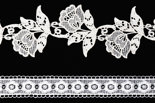 White lace with flowers and leaves isolated on black background horizontally