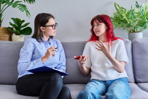 Psychologist counseling teenage female, individual therapy in doctors office. stock photo
