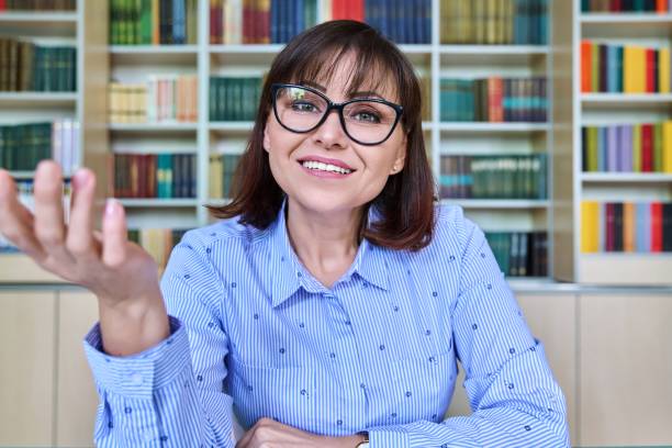 istock Female teacher in the library talking looking at the webcam, close-up face 1408600548