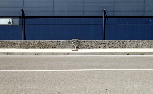 Low street lamp on concrete sidewalk with small cement fence and dark blue wall on behind. Asphalt street in front. Background for copy space.