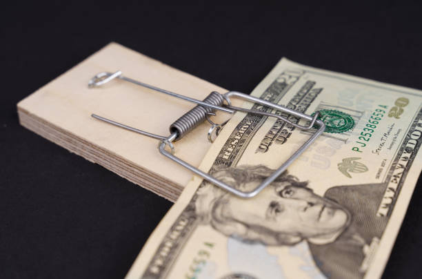 istock Twenty dollar bill in a wooden mousetrap on a black background. 1408603610