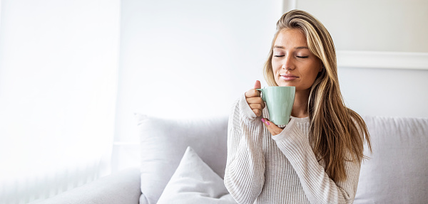 Side view of Happy brunette woman drinking coffee. Middle aged woman drinking tea while thinking. Relaxing and thinking while drinking coffee.