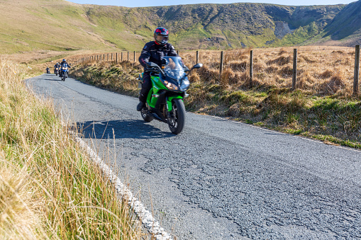 A group of motorcyclists riding in Welsh countryside along a rural road on the Abergwesyn Pass between Tregaron and Llanwrtyd Wells.