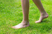 Barefoot feet walking on fresh green grass lawn