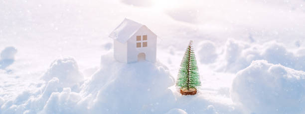 istock Decorative white house with a spruce tree in the snow in the sunlight outdoors, free space 1408609097