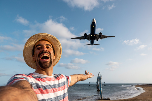 Happy man taking a selfie at the airport with airplane landing