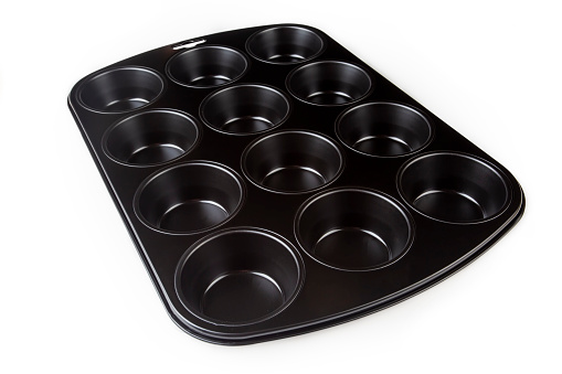 Muffin cake pan with non-stick coating isolated on a white background. 12-cup muffin baking tray. Empty cupcake bake ware for pie, tart, cake and pastries concepts. Kitchen utensils. Top view.