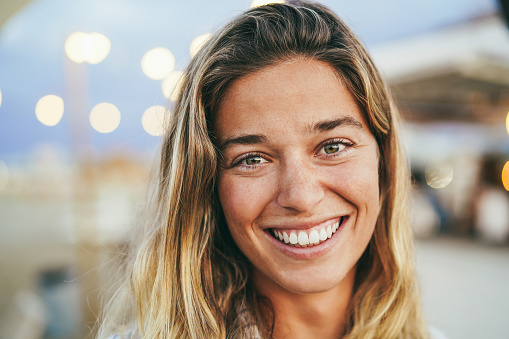 Young girl smiling on camera with beach bar on background - Soft focus on eyes
