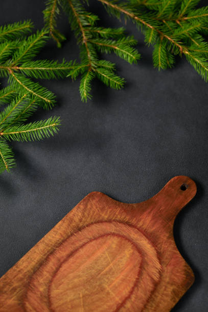 istock Vertical photo Black Table with Green Branches and Empty Kitchen Board. Old wooden board for meat. 1408612879