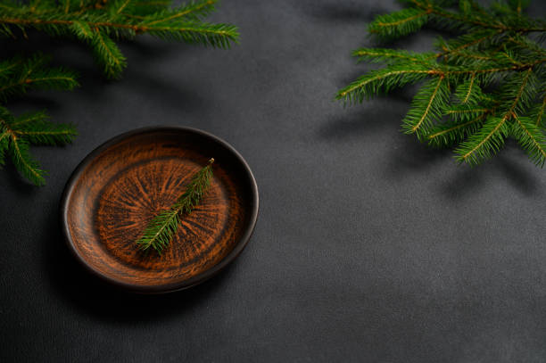 istock An old Clay plate stands on the Black Table. Empty plate with green twig. Christmas theme. 1408613616