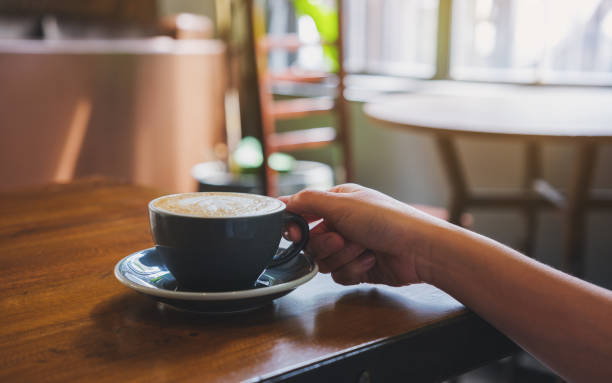 istock Closeup image of a hand holding coffee cup on wooden table 1408614347