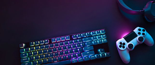 Top down view of colorful illuminated gaming accessories laying on table. Professional computer game playing, esports business and online world concept.