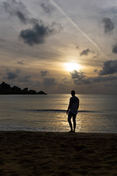istock Unrecognizable young man watching the sunset on the beach shore 1408616705
