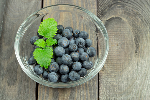 Some blueberries in a small transparent bowl with mint leaves close-up photography