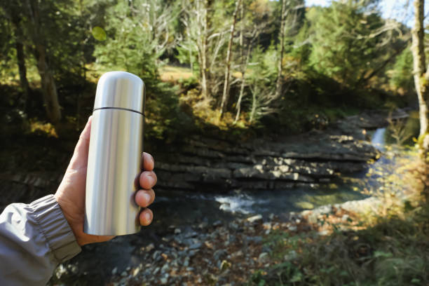 istock Man with thermos near mountain river, closeup. Space for text 1408622721
