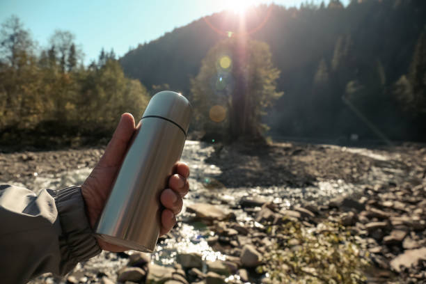 istock Man holding thermos in mountains, closeup. Space for text 1408622722