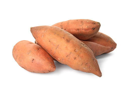 Heap of whole ripe sweet potatoes on white background