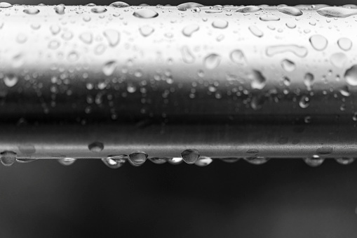 Raindrops separated out on a metal rail.