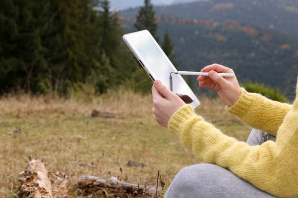 istock Woman drawing with graphic tablet in mountains, closeup 1408624240