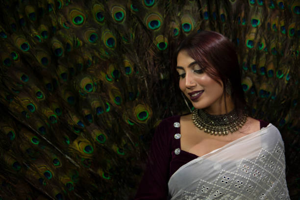 retrato de vista lateral de uma mulher indiana tímida, bonita e elegante, usando joias e sari. ela está olhando para baixo e sorrindo. - bird fashion color image women - fotografias e filmes do acervo