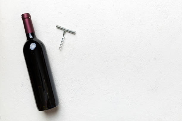 one bottle of red wine with corkscrew on colored table. flat lay, top view wth copy space - cork tops imagens e fotografias de stock