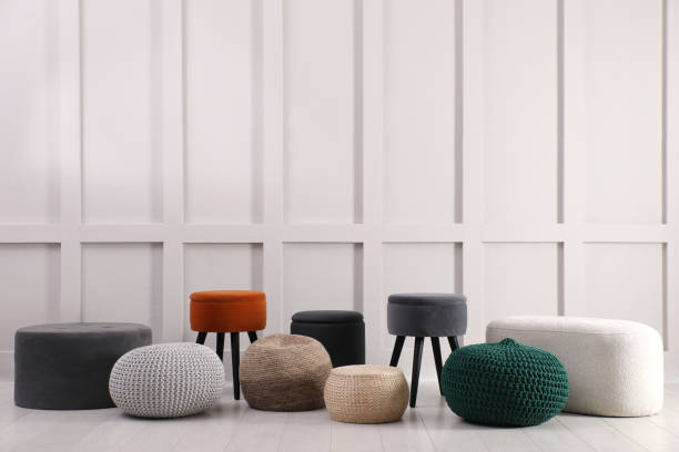 istock Different stylish poufs and ottomans near light wall 1408626604