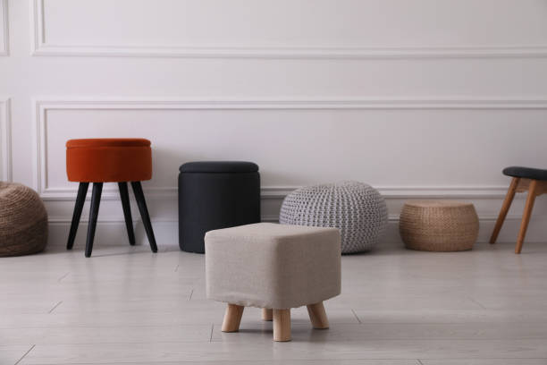 istock Different stylish poufs and ottomans near light wall 1408626681